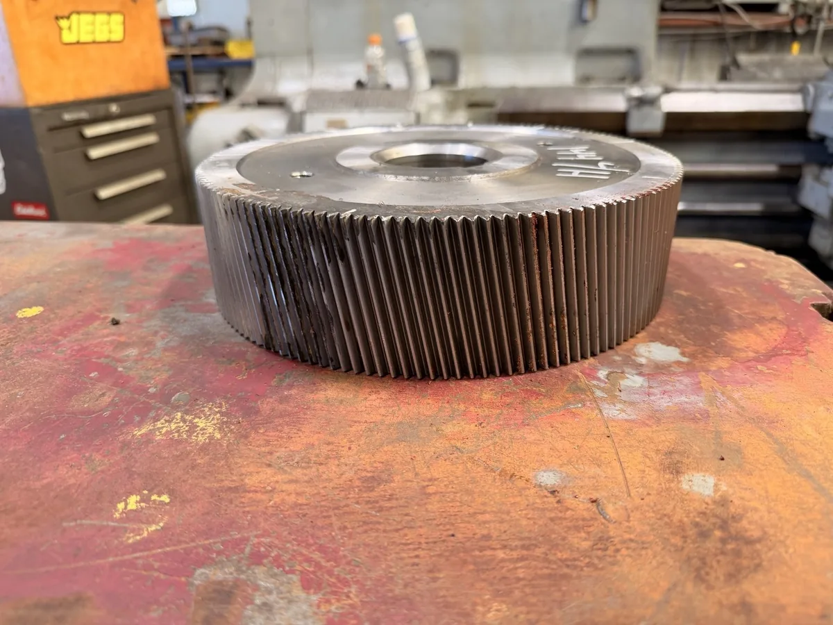 Helical gear on the workbench showing its tooth face and machined hub.